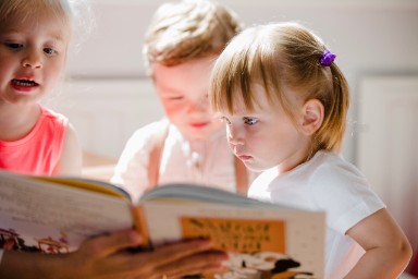 Foto van peuters die een prentenboek bekijken op de kinderopvang