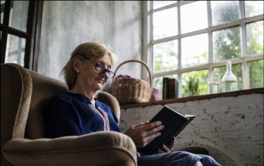 Afbeelding van een zittende vrouw die een boek leest. 