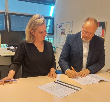 Foto van Kees Nieuwkoop (Yuverta) en Marloes Middeldorp (bibliotheek Gouda) die de samenwerkingsovereenkomst ondertekenen